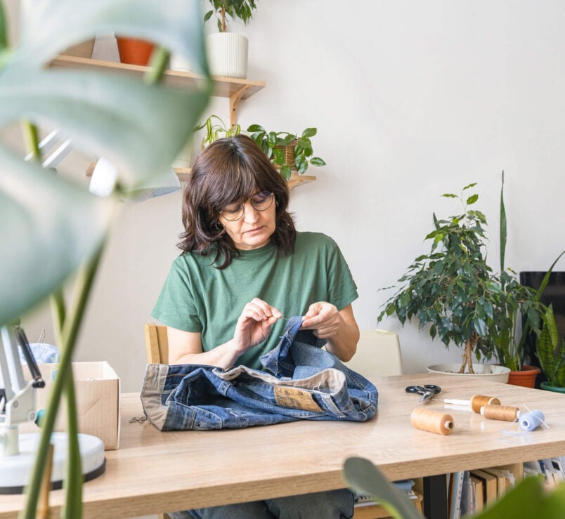 Adult woman mending blue denim pants