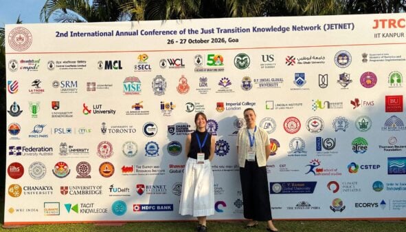 2 people in front of display board with partner logos